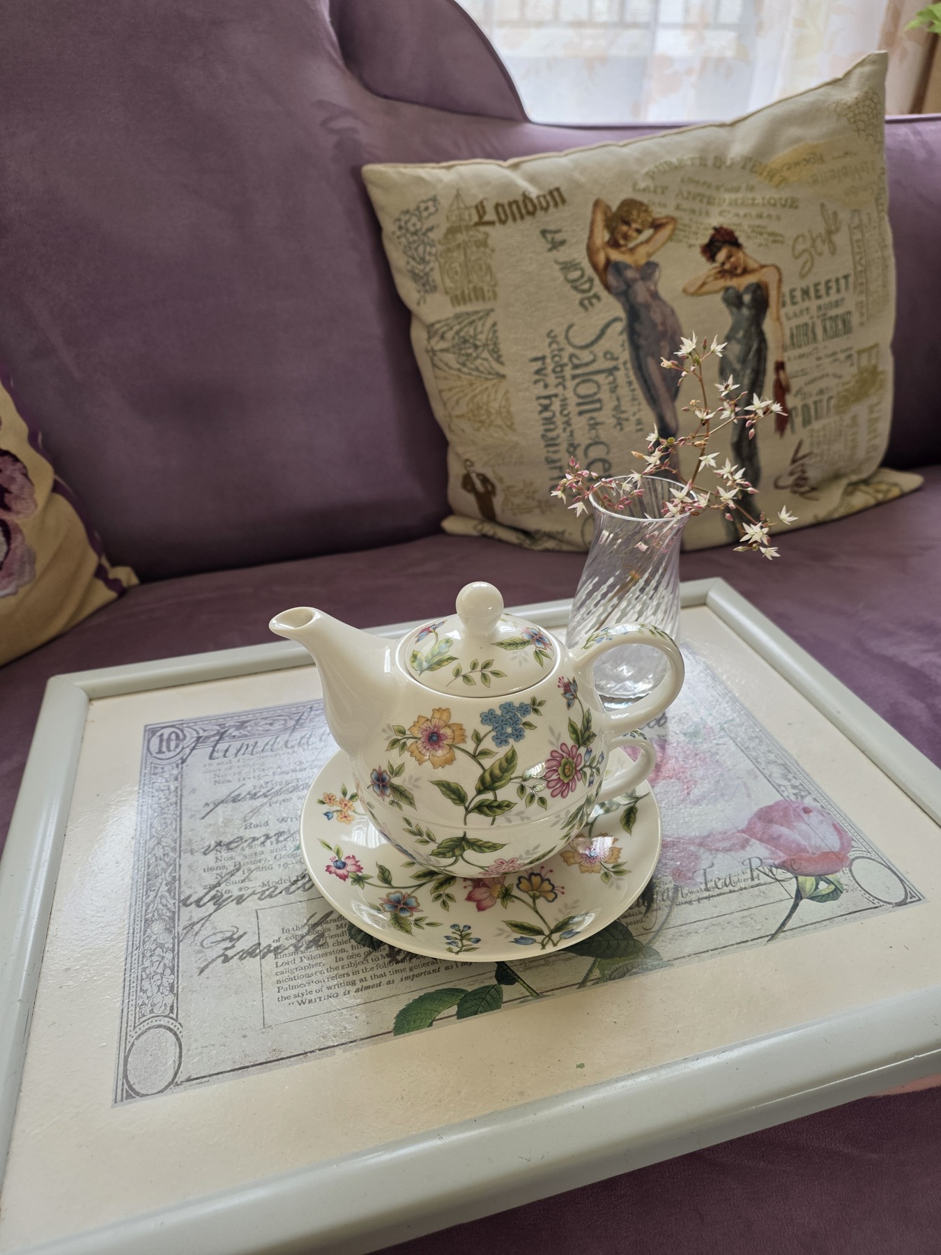 Wild garden flowers in a small crystal vase beside a floral teapot on a rose-decorated tray