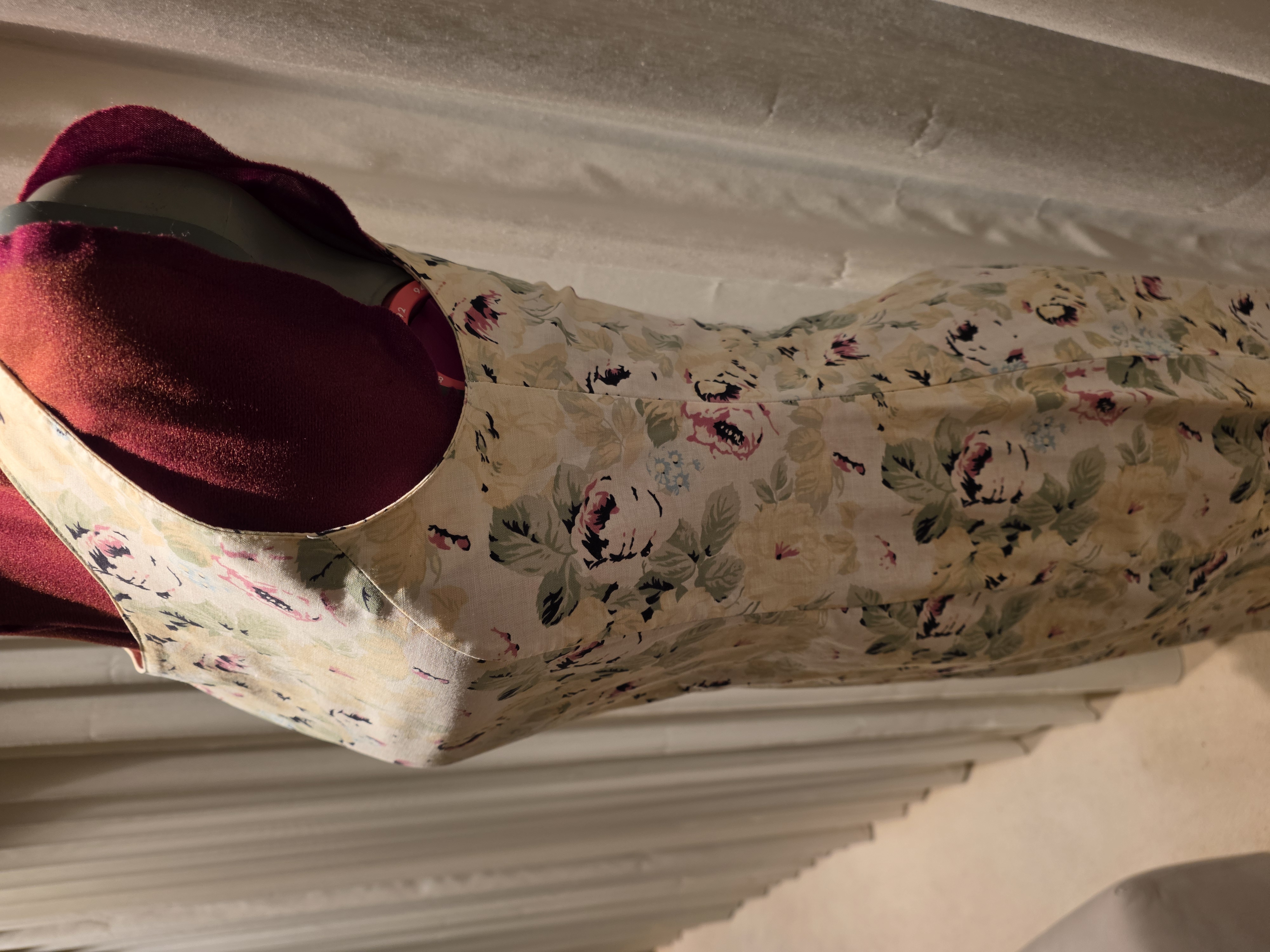 Side view of the cream floral dress showing its fitted waist and shaping through the bodice