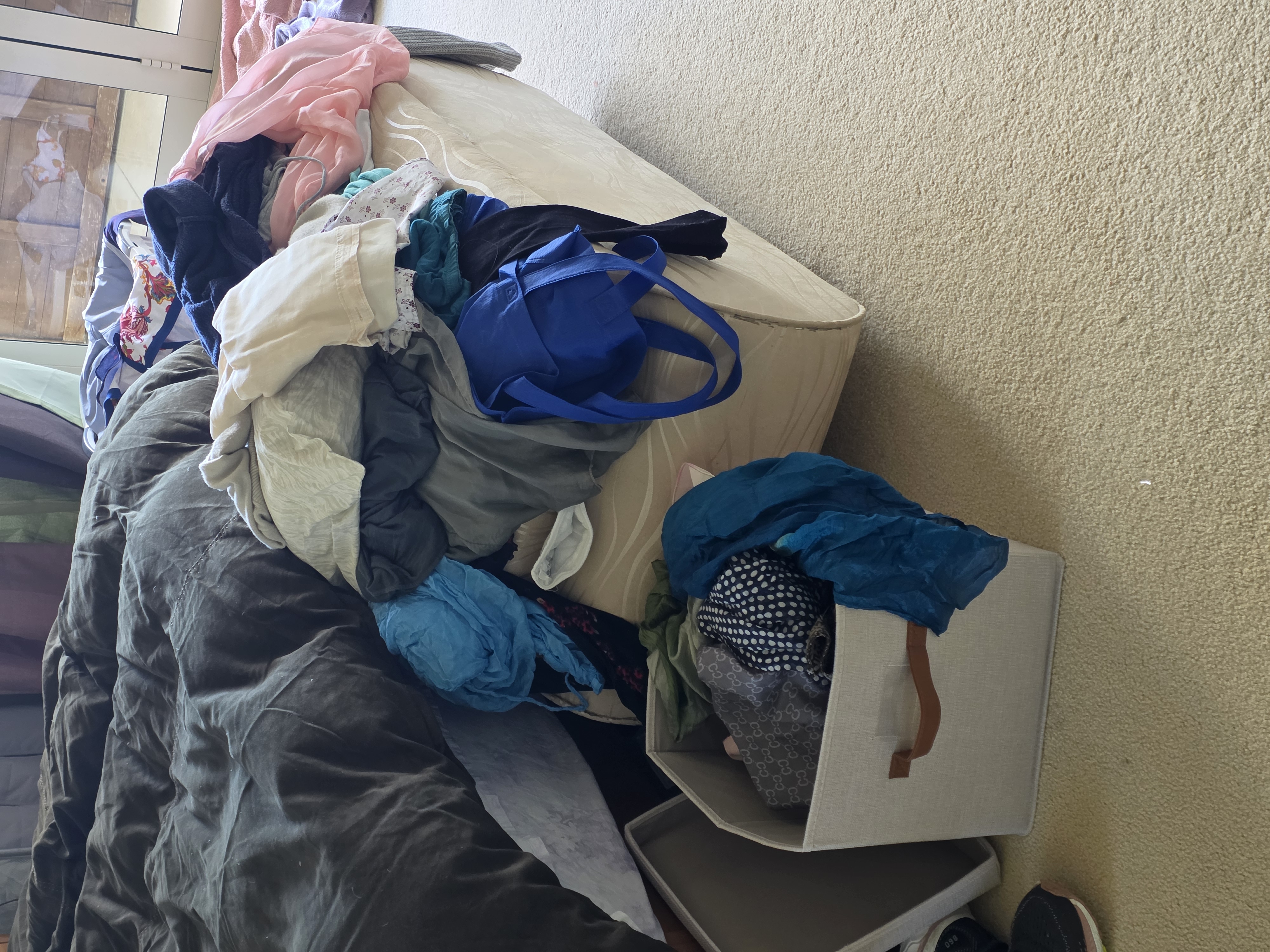 Clothes temporarily laid out on a bed during a wardrobe sort